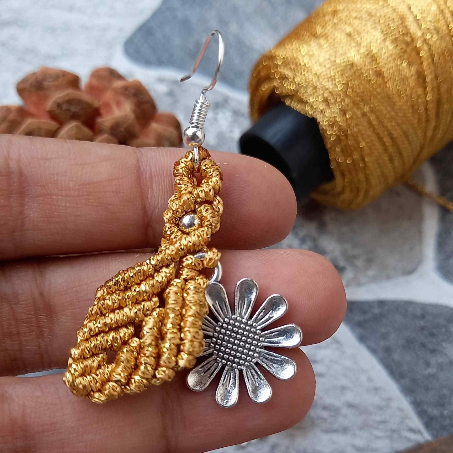 macrame dangler earrings featuring a single leaf over a silver daisy charm