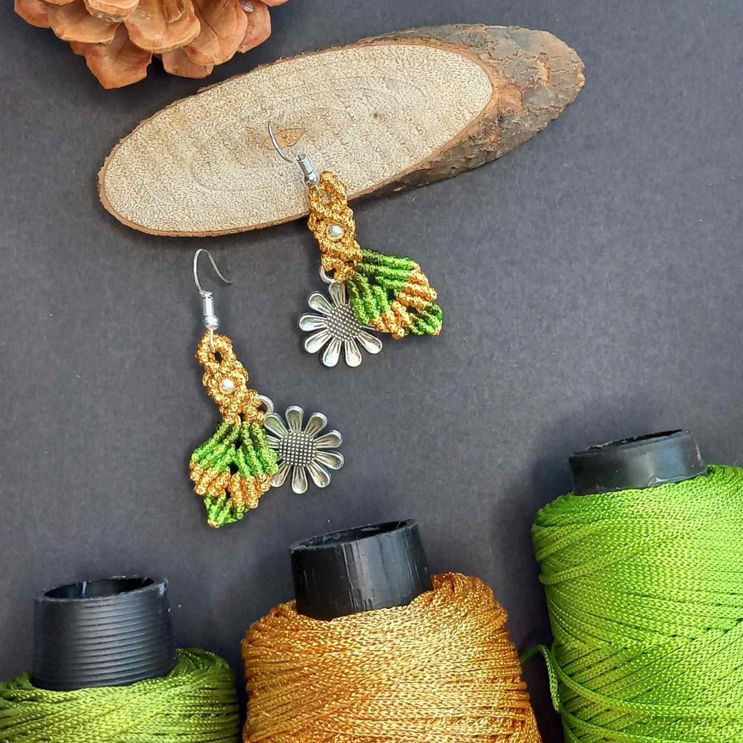 macrame dangler earrings featuring a single leaf over a silver daisy charm