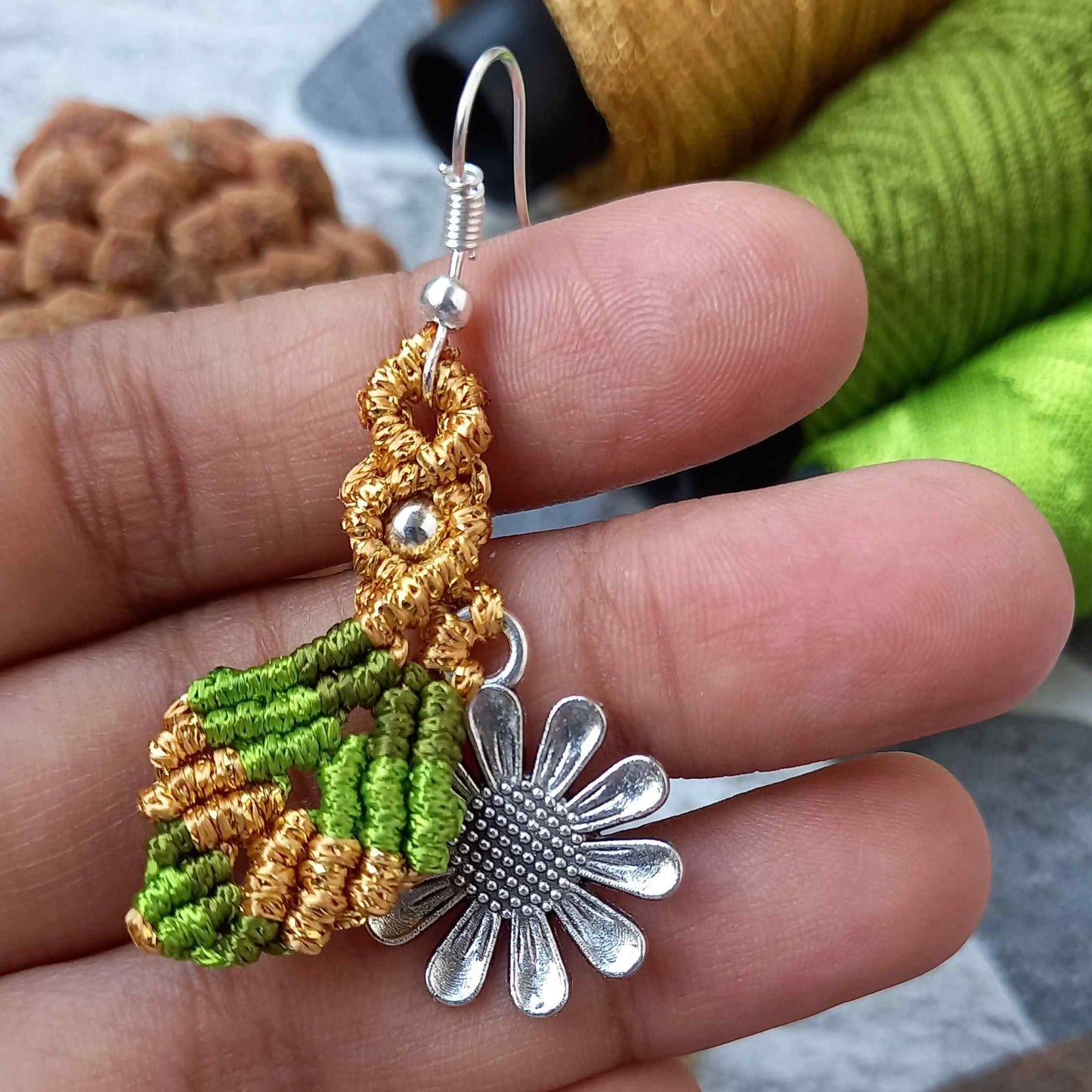 macrame dangler earrings featuring a single leaf over a silver daisy charm