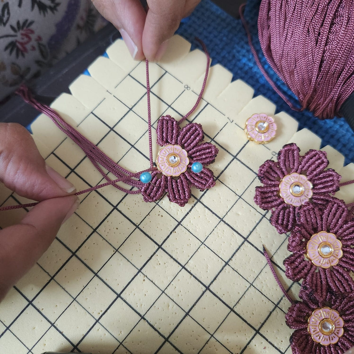 Hand-knotted macrame necklace in progress, showing the threadwork behind a handmade festive necklace set