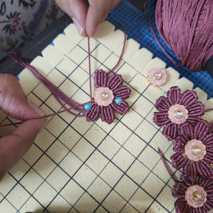Hand-knotted macrame necklace in progress, showing the threadwork behind a handmade festive necklace set