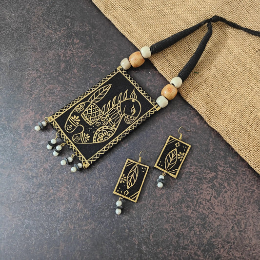 Vastrika black fabric necklace set — black cotton pendant with a horse hand-painted in gold, a cowrie shell dangle and gold leaf-motif earrings