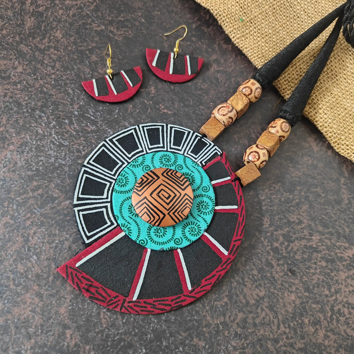 Vasudha fabric necklace set — spiral pendant in maroon, black and light blue fabric with black and white hand painting and a copper-painted clay centre