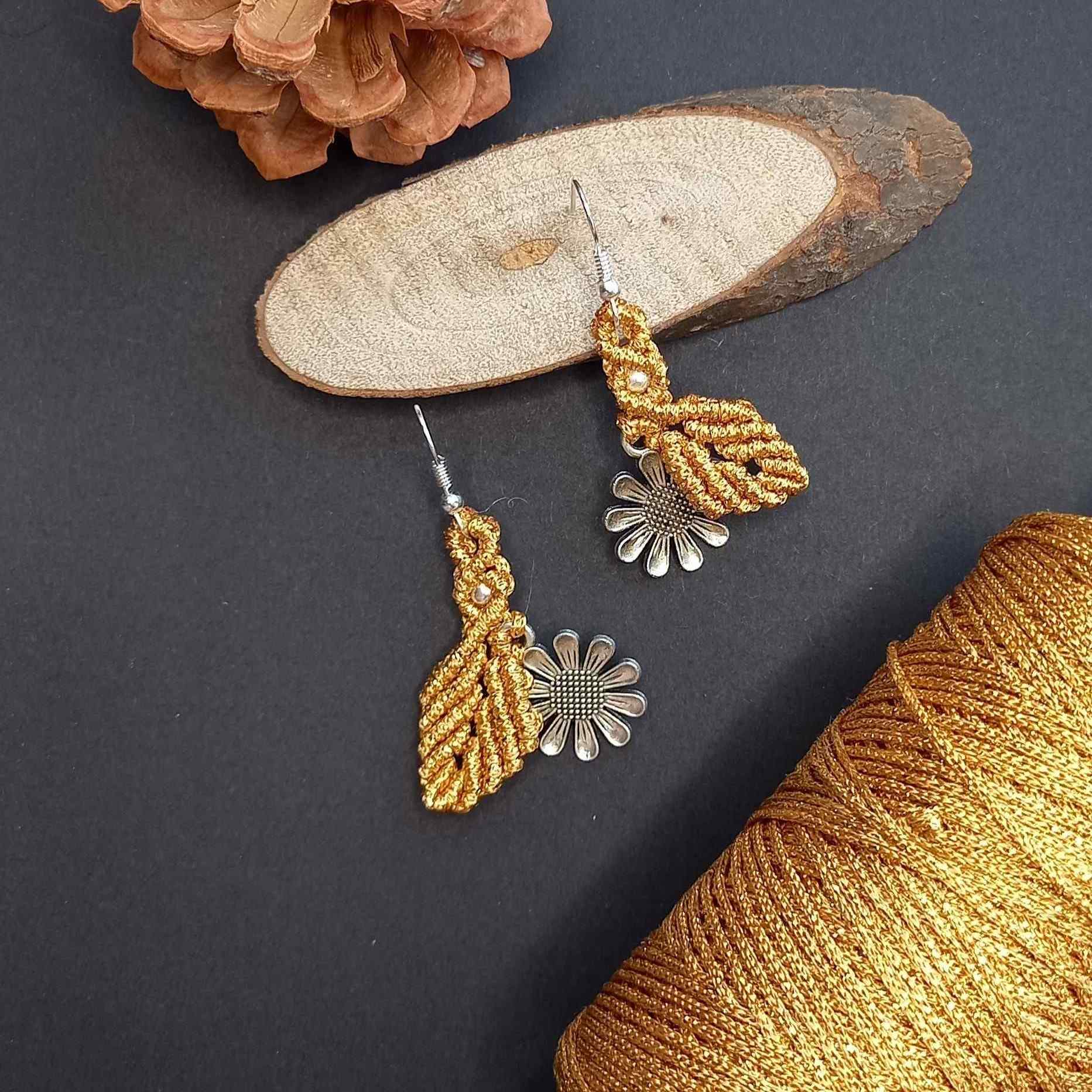 macrame dangler earrings featuring a single leaf over a silver daisy charm